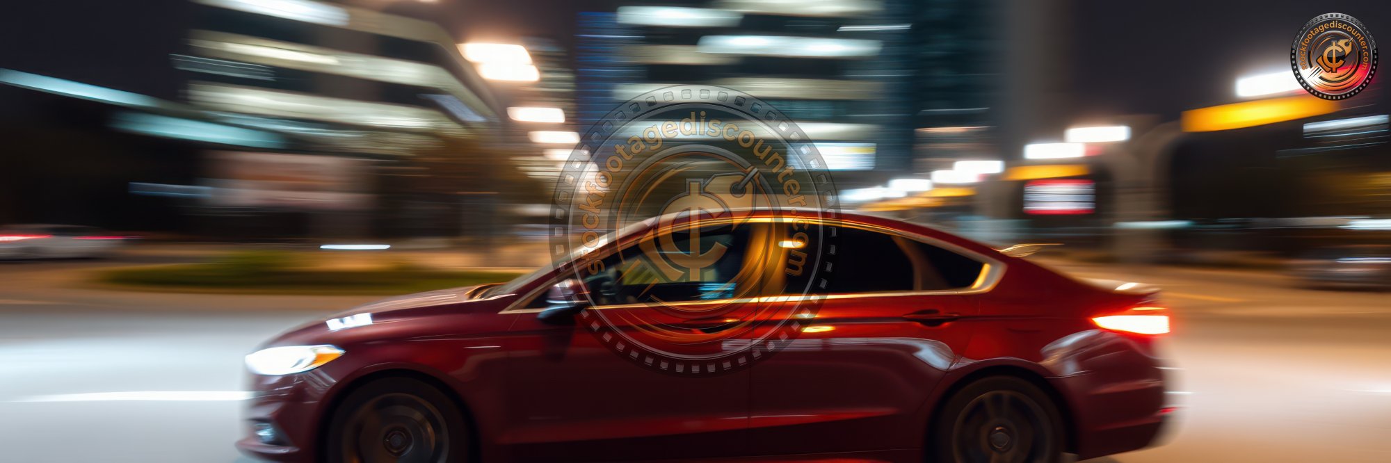Red sedan speeds through urban streets at night, showcasing dynamic motion and city lights