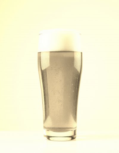A   s i n g l e ,   c l e a r   g l a s s   f i l l e d   w i t h   a   g o l d e n - h u e d   b e e r   t o p p e d   w i t h   a   l a y e r   o f   w h i t e   f o a m   r e s t s   o n   a   p l a i n   w h i t e   s u r f a c e