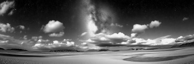 T h e   M i l k y   W a y   s t r e t c h e s   a c r o s s   t h e   s k y   a b o v e   a   d e s e r t   l a n d s c a p e   w i t h   d i s t a n t   m o u n t a i n s