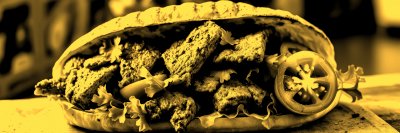 D e l i c i o u s   s a n d w i c h   f i l l e d   w i t h   g r i l l e d   m e a t ,   f r e s h   t o m a t o e s ,   a n d   l e a f y   g r e e n s   p r e p a r e d   i n   a   c o z y   k i t c h e n   s e t t i n g